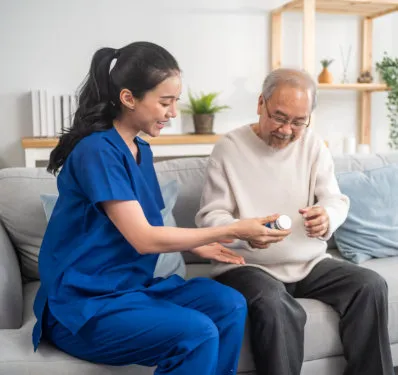 A nurse going over medication with an older man in his living room
